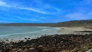 A rocky beach with a view of the ocean and distant hills. - Lewcott (Sennen)