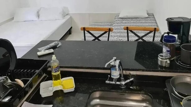 Kompakti hotellihuone, jossa on pieni keittiönurkkaus, sänky, televisio ja pieni ruokailutila.