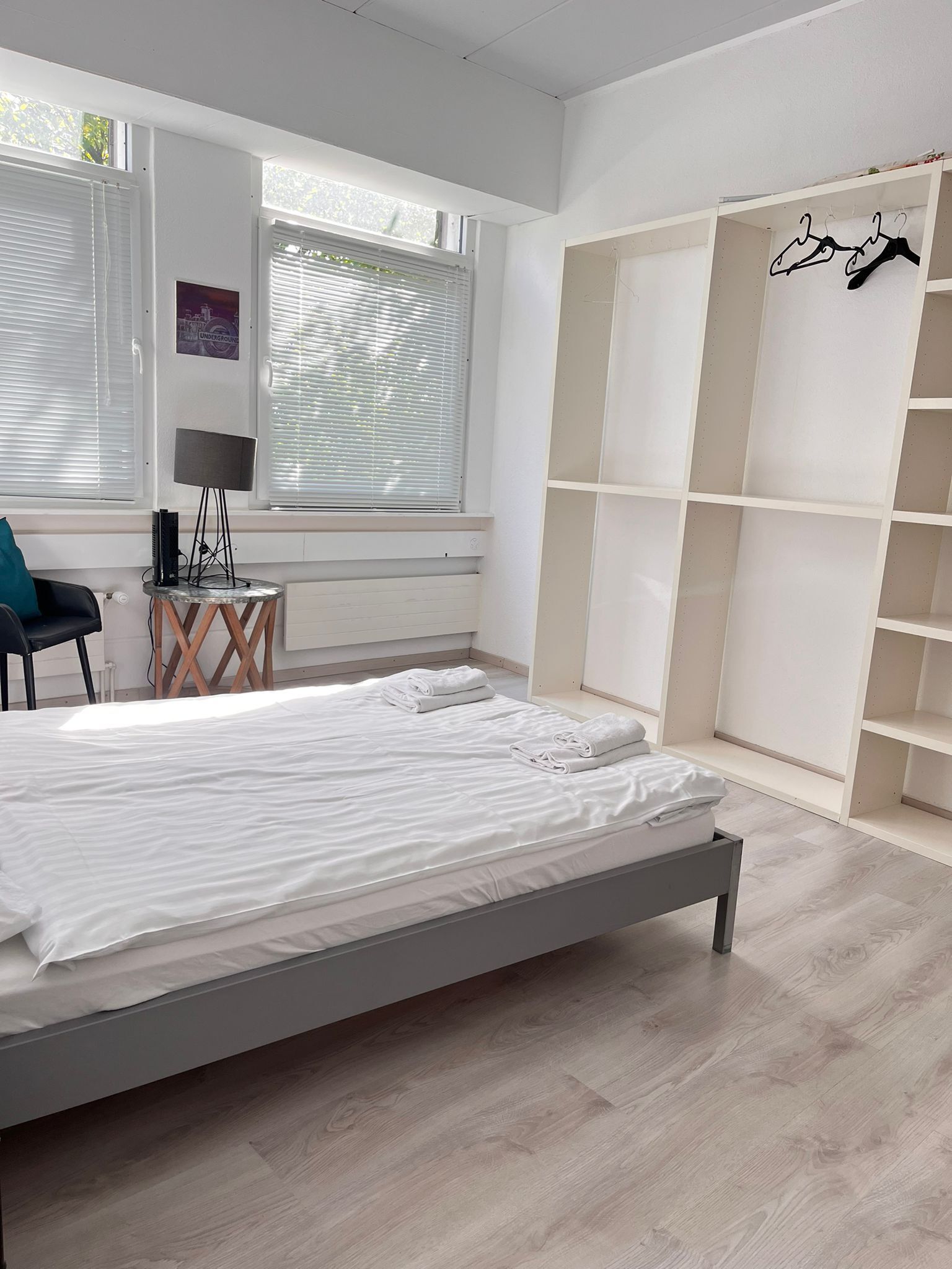 Une chambre moderne avec un lit, un bureau doté d’une lampe et une armoire avec un espace pour suspendre les vêtements.