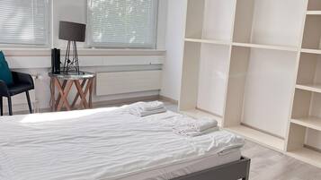 Une chambre moderne avec un lit, un bureau doté d’une lampe et une armoire avec un espace pour suspendre les vêtements.