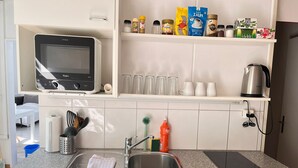 A modern kitchen with a built-in microwave, stainless steel sink, and a countertop with various kitchen items. - Bright, comfy, industrial looking (Fällanden)