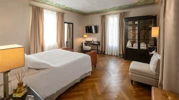 A hotel room with a large bed, a desk, a TV, and a seating area.