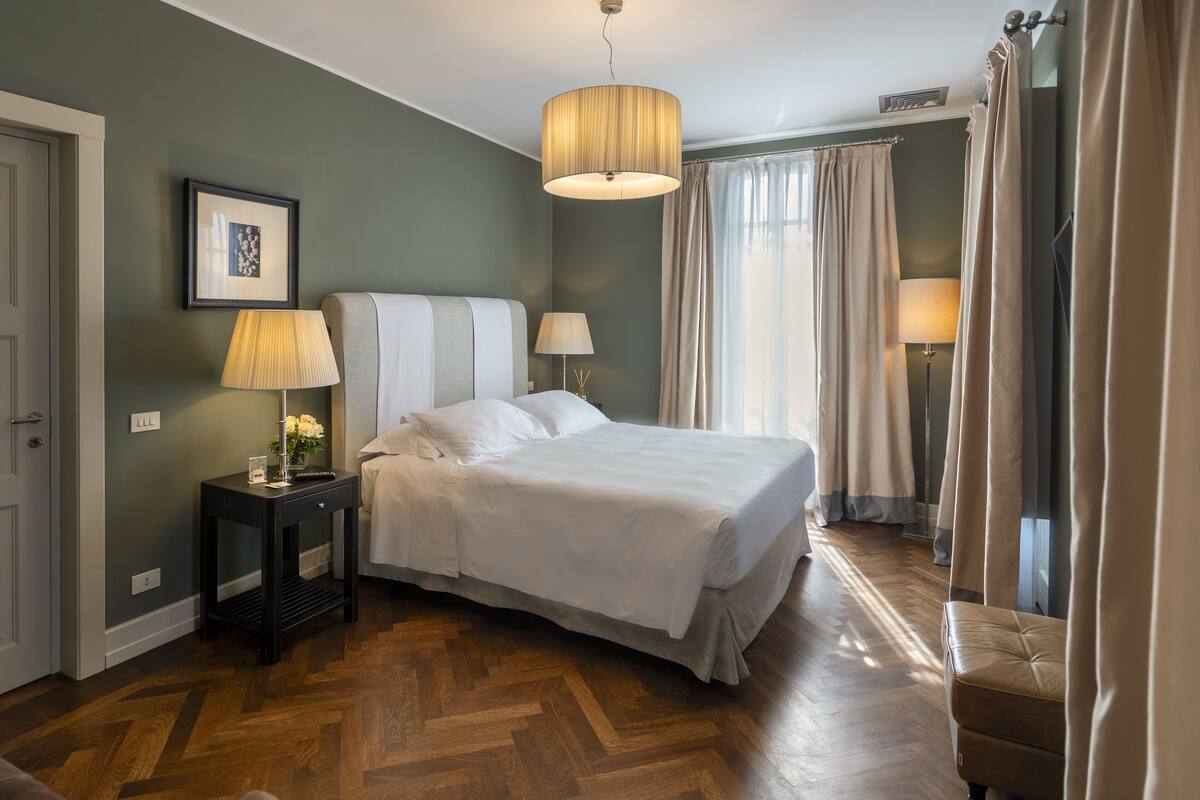 Une chambre bien rangée, avec un lit, des lampes de chevet, un tableau encadré et un plancher en bois.