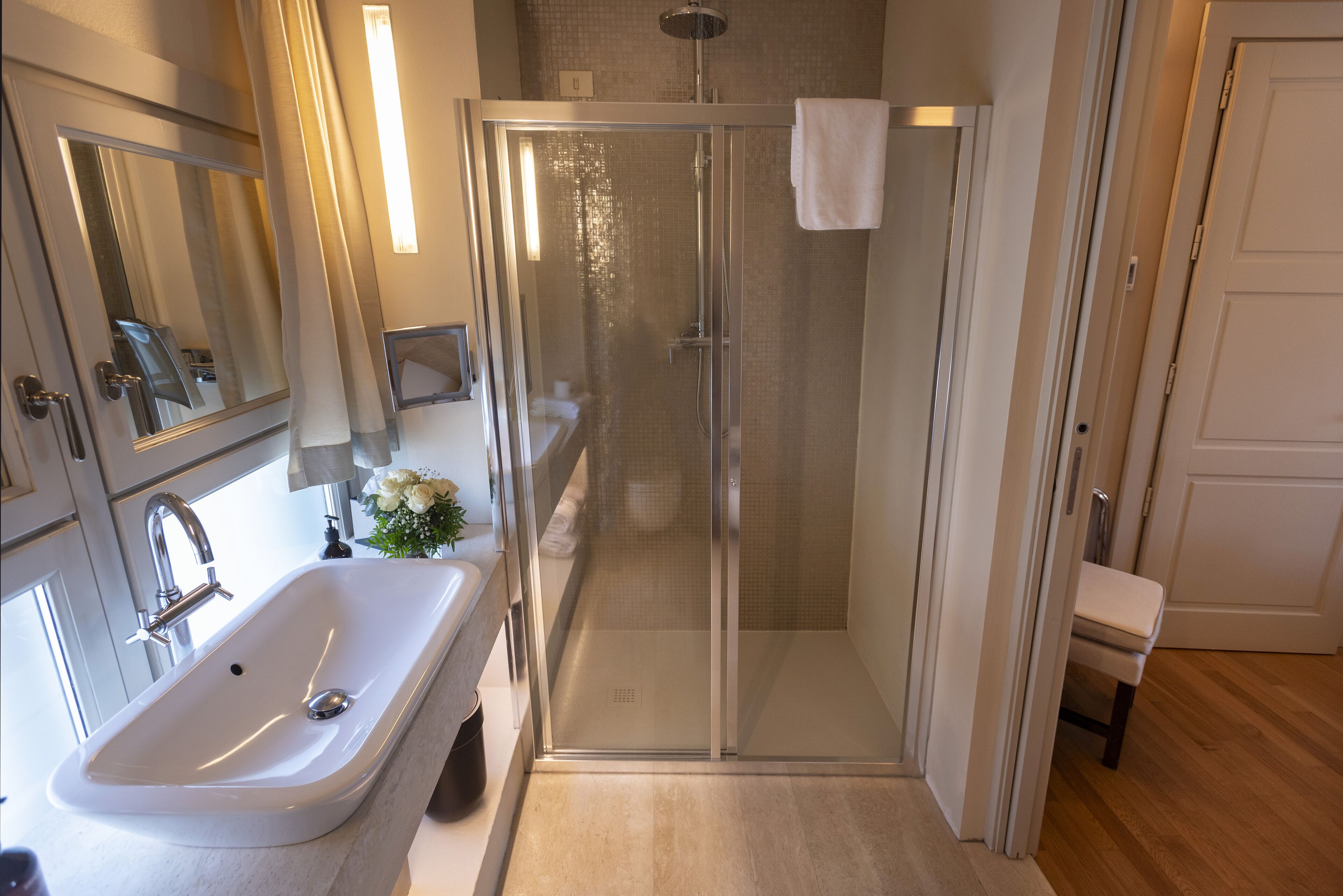 A bathroom with a glass-enclosed shower, a sink, and a mirror.