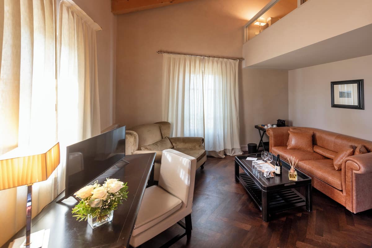 Un salon avec un plafond en bois, un canapé en cuir marron, une table à manger avec des chaises et une table basse ornée d’un vase de fleurs.