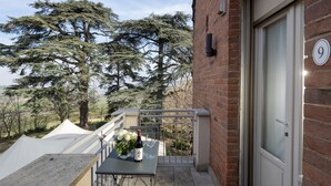 Un balcon avec une table dressée pour deux personnes, une bouteille de vin et un vase de fleurs.