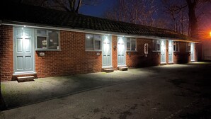 A row of brick buildings with multiple doors, each with a small step leading up to the entrance. - Arlan House Hotel (Basingstoke)