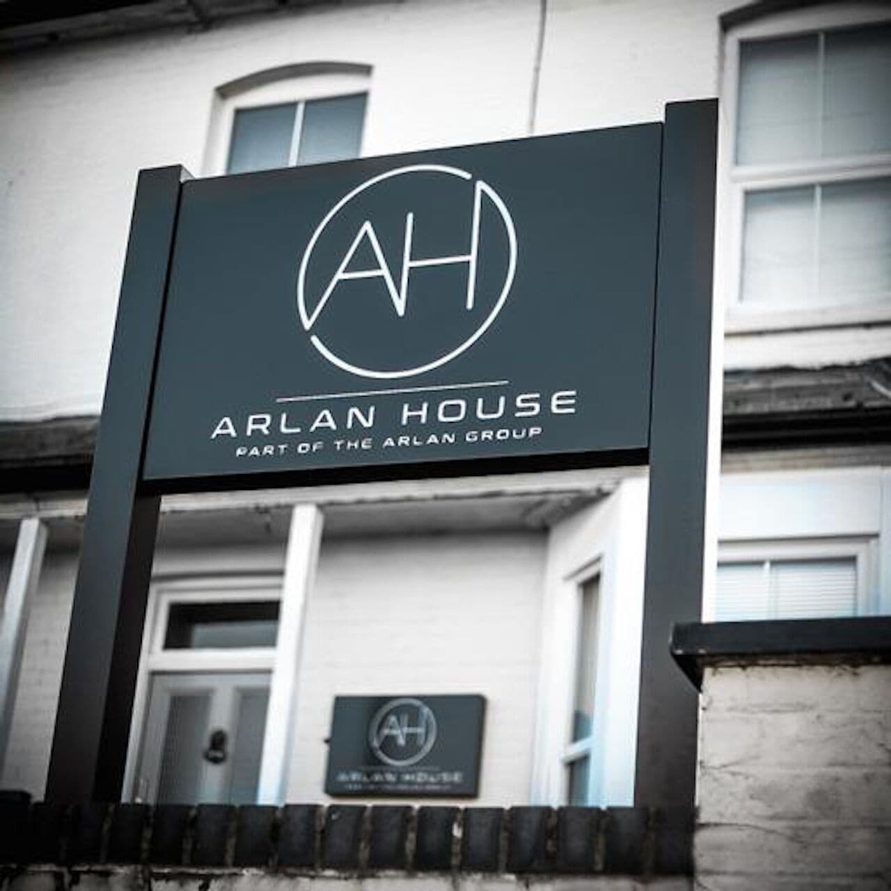 A sign for Arlan House, part of the Arlan Group, with a simple logo and text.