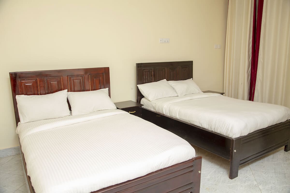 Two single beds with wooden headboards in a room with cream walls and a tiled floor.