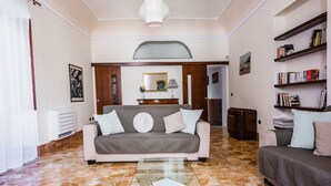 A living room with a sofa, a coffee table, a bookshelf, and a decorative mirror. - La Maison di Ortigia (Syracuse)