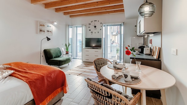 Une pièce moderne et bien éclairée, comprenant un lit, un coin repas et une cuisine.