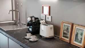 Une cuisine moderne avec un plan de travail noir, une machine à café, un grille-pain et deux tableaux encadrés accrochés au mur.
