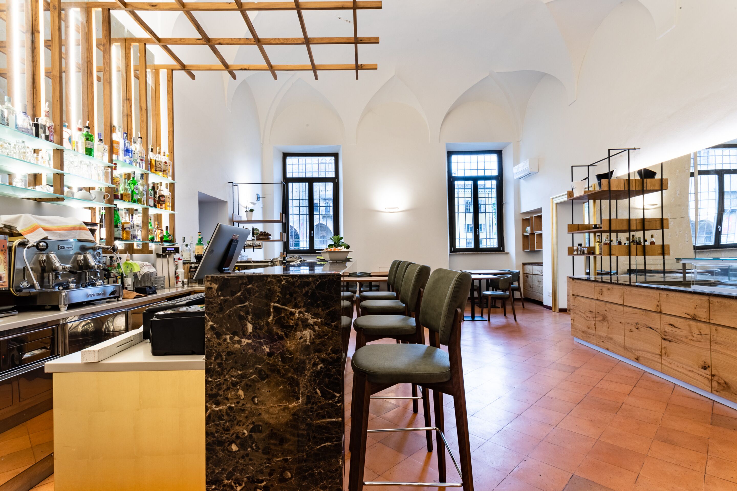 Un bar moderno con mostradores de mármol, estanterías de madera y taburetes.