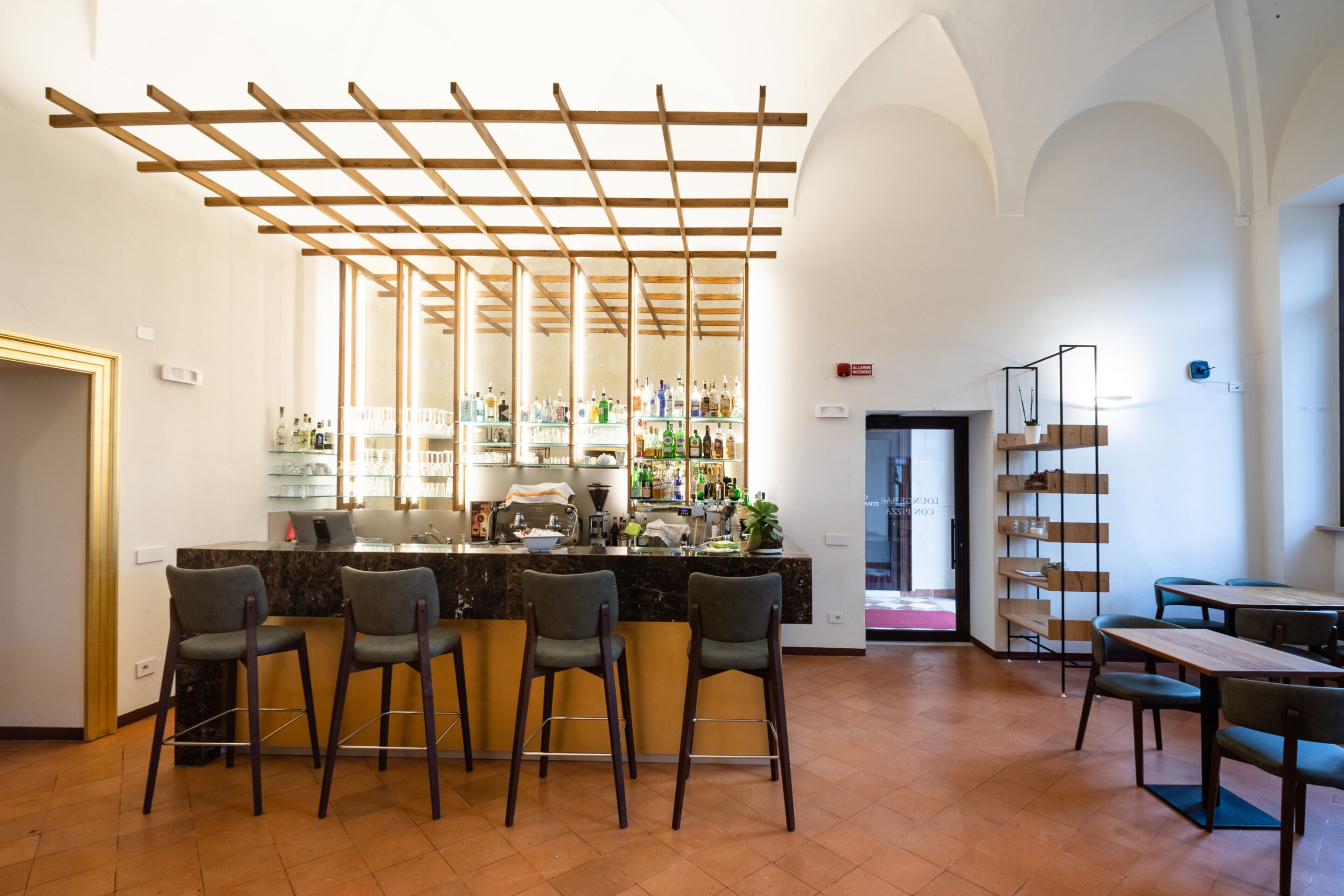 A bar area with a wooden ceiling, bar stools, and a counter with various bottles.