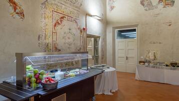 Un buffet proposant une grande variété de plats, une table blanche recouverte d’une nappe et un mur orné de fresques décoratives.