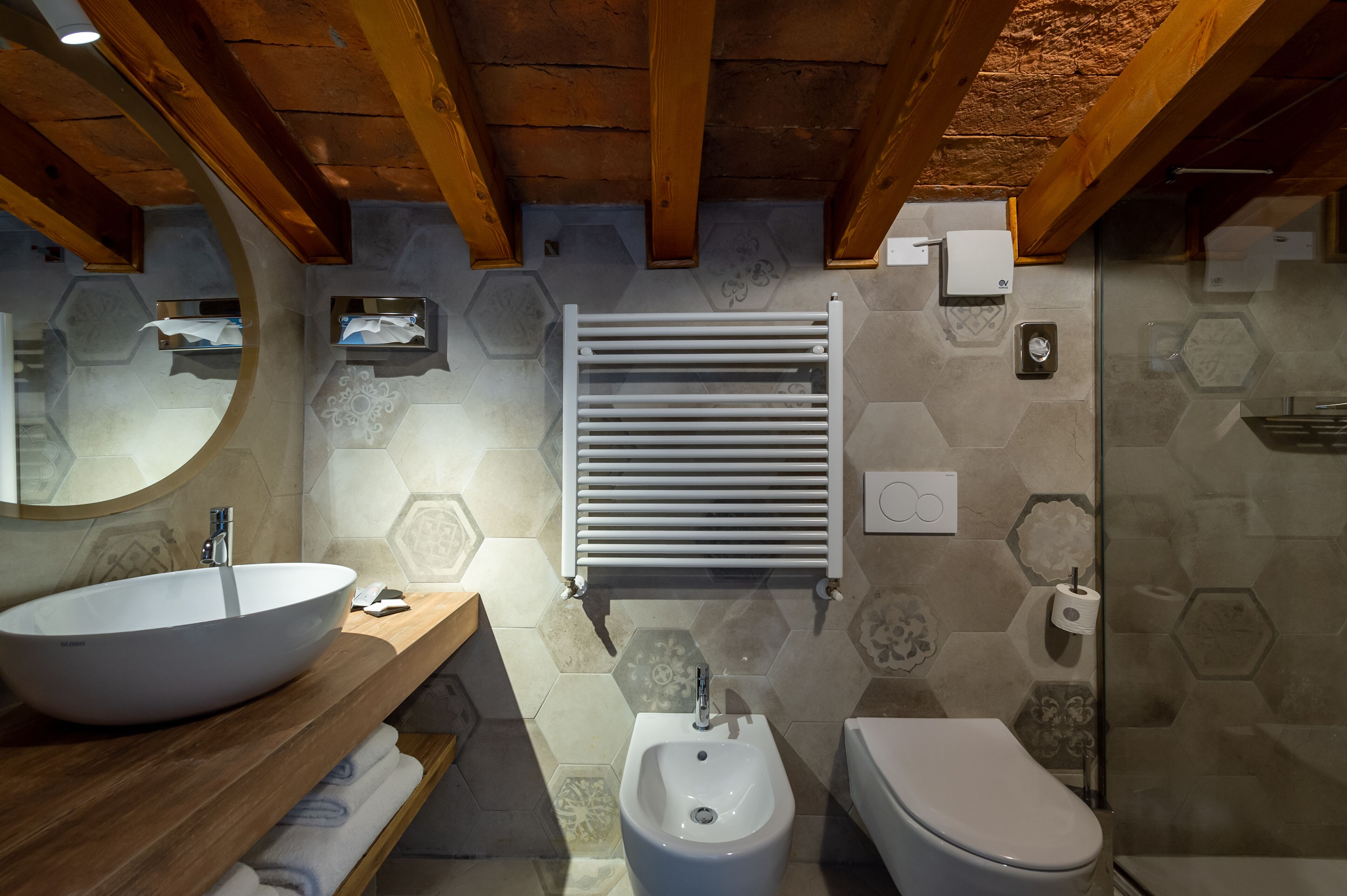 Une salle de bain moderne avec un plafond en bois, un grand lavabo sur pied, un bidet et des toilettes.