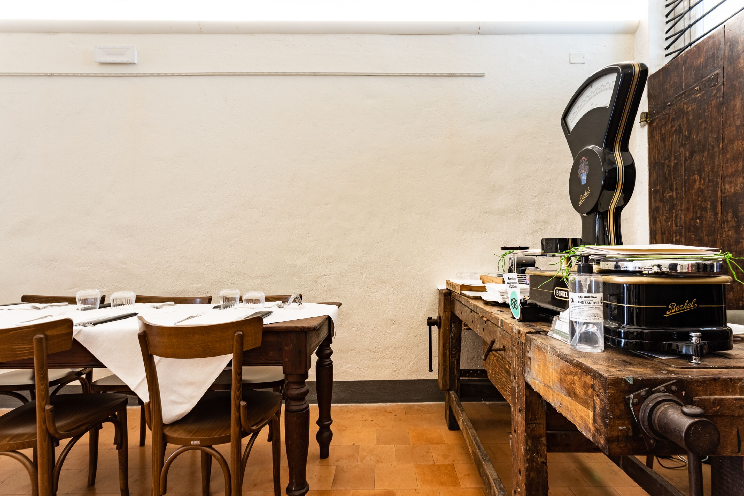 A dining area with wooden tables and chairs, a vintage jukebox, and a wooden counter with various items.
