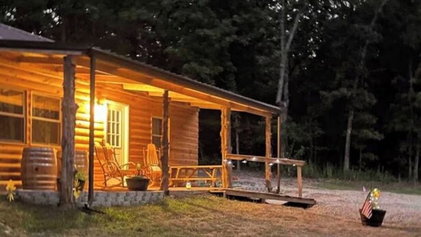 Une cabane en bois avec une véranda, un banc et une petite table.