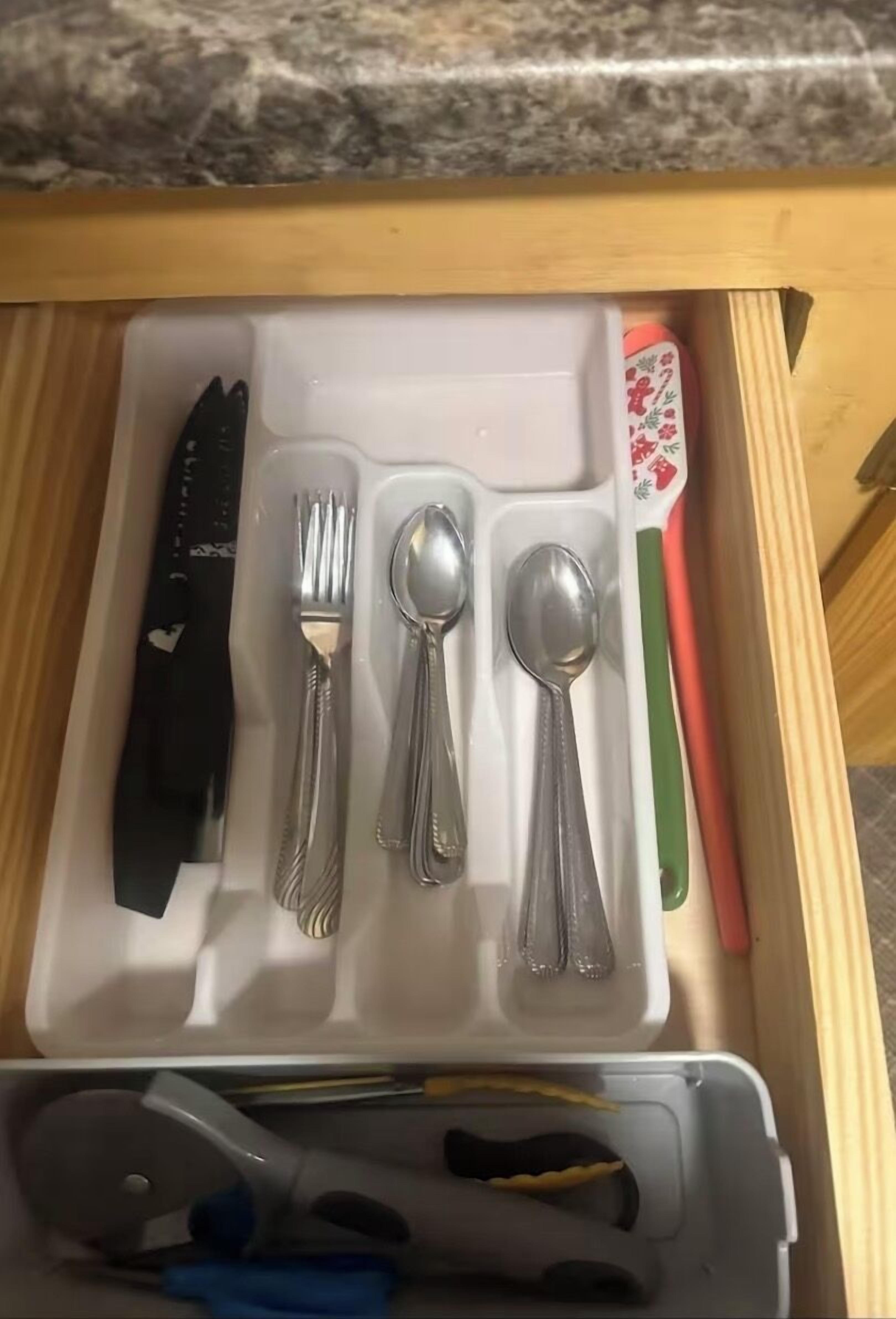 Un cajón con cubiertos y un cuchillo.