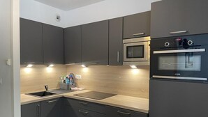 A modern kitchen with dark cabinets, a stainless steel sink, a microwave, and a built-in oven.