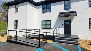 A modern building with a white facade, black-framed windows, and a black door. - The Traveler on Main - Suite #6- Across the Street from Back of the Dragon! (Tazewell)