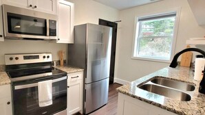 A modern kitchen with stainless steel appliances, a double sink, and a window providing natural light. - The Traveler on Main - Suite #6- Across the Street from Back of the Dragon! (Tazewell)