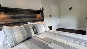 A bedroom with a wooden headboard, a bed with a striped quilt, two bedside lamps, and a white door.