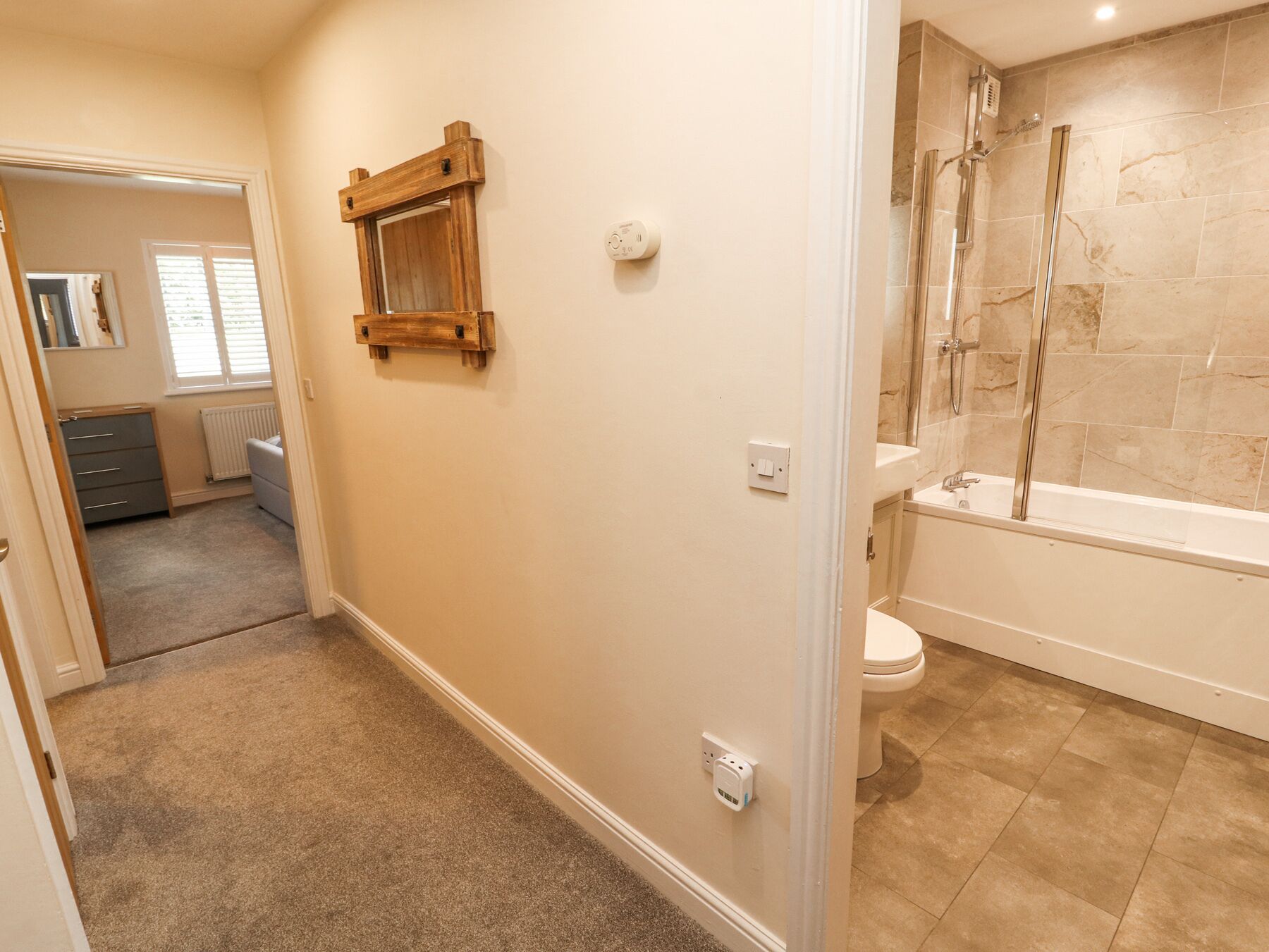 A bathroom with a shower, toilet, and a wooden shelf.