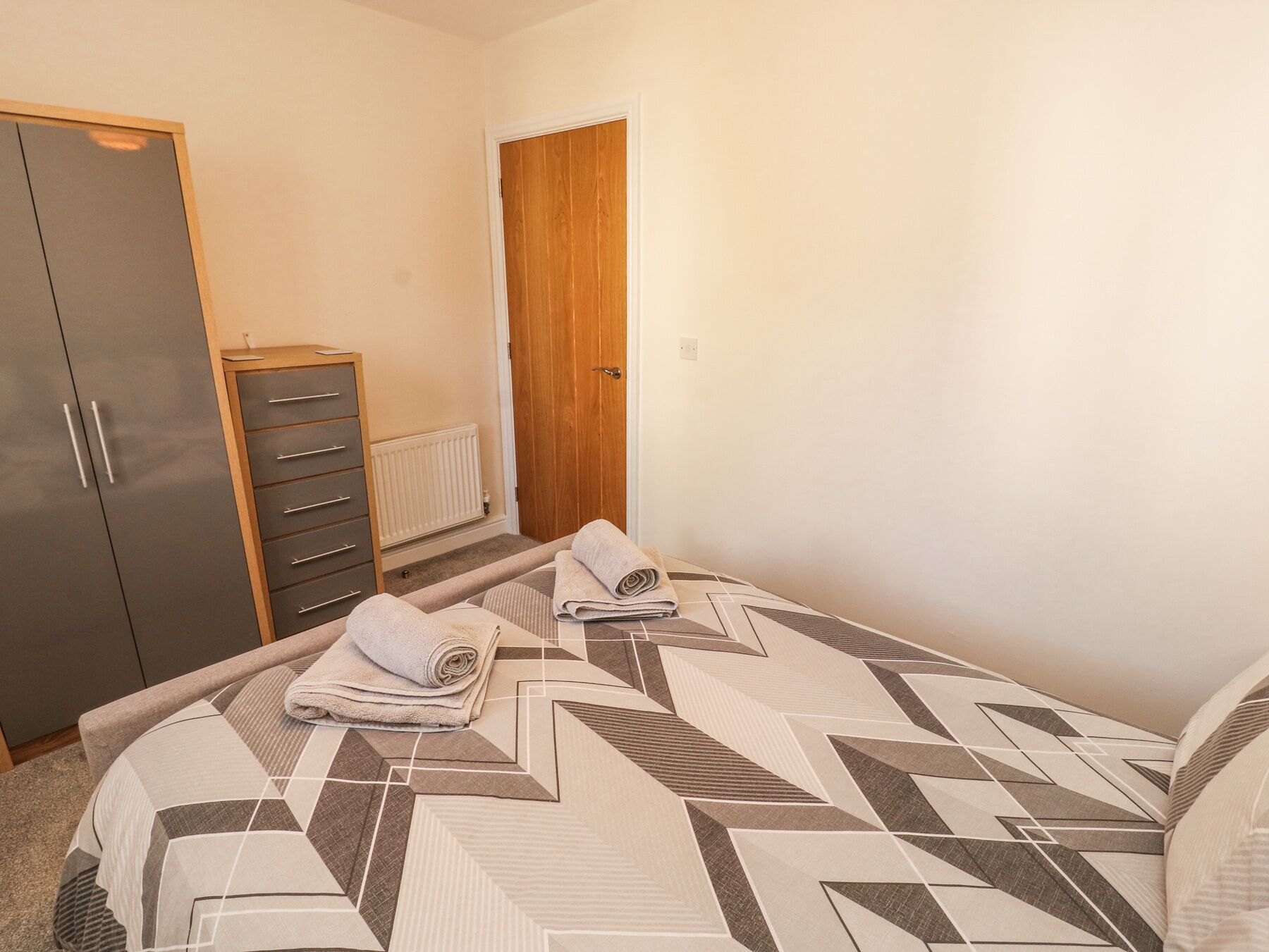 Ein Schlafzimmer mit Bett, Kleiderschrank, Kommode und einer Tür.