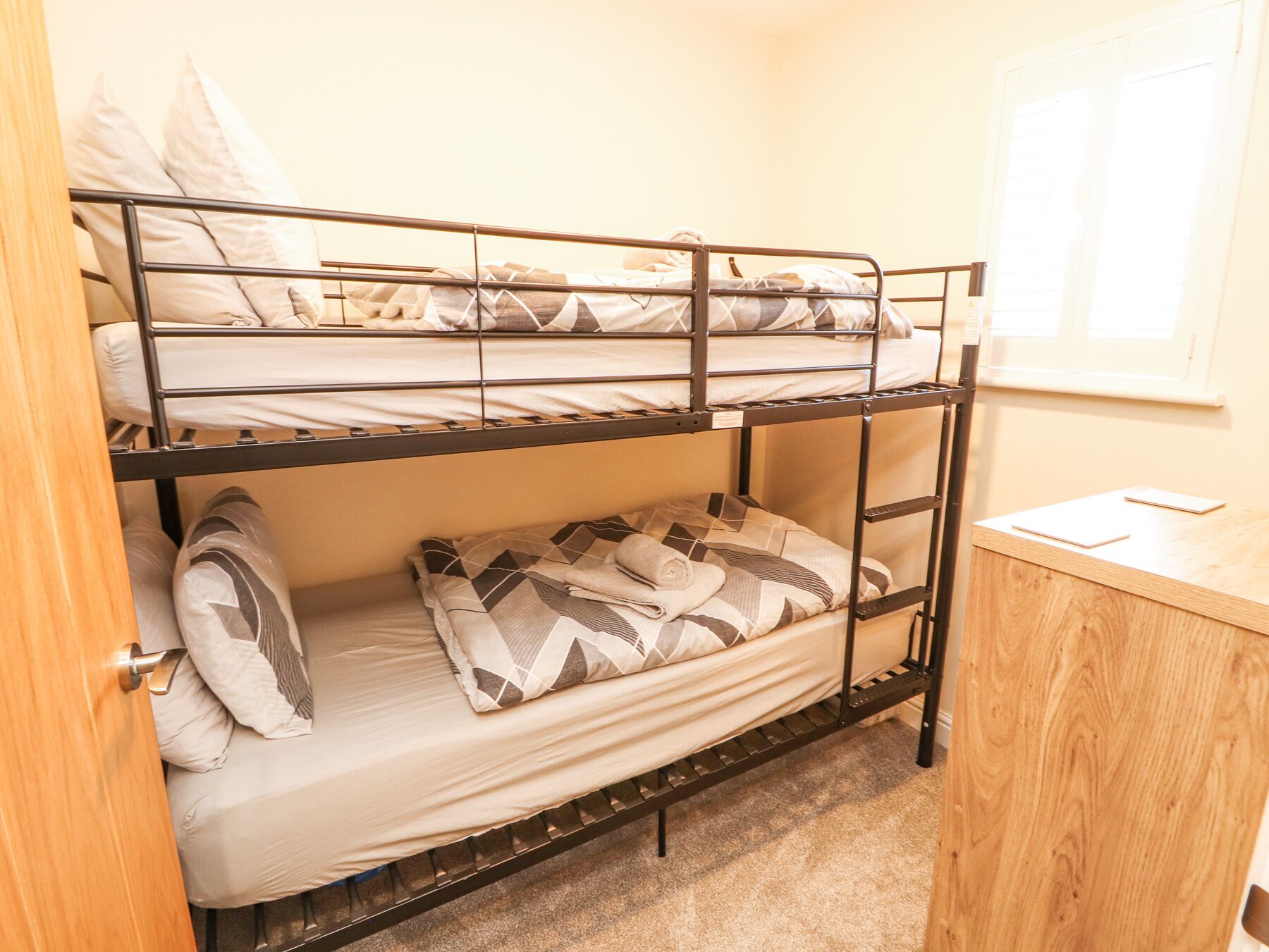 Dormitorio con literas, una puerta de madera y una ventana.
