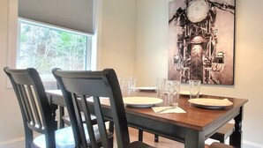 A dining table with four chairs, a painting on the wall, and a window with blinds. - The Traveler on Main - Suite #4- Across the Street from Back of the Dragon! (Tazewell)