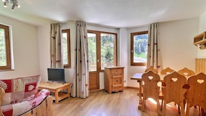 A cozy room with a wooden sofa, a small table with a laptop, a wooden cabinet, and a dining table with heart-shaped chairs. - 50m from ski slopes, 5th floor, balcony, ski locker, 41m², La Tania (Courchevel)