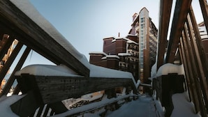 A snow-covered wooden staircase leading to a building with multiple floors and balconies. - 50m from ski slopes, 5th floor, balcony, ski locker, 41m², La Tania (Courchevel)
