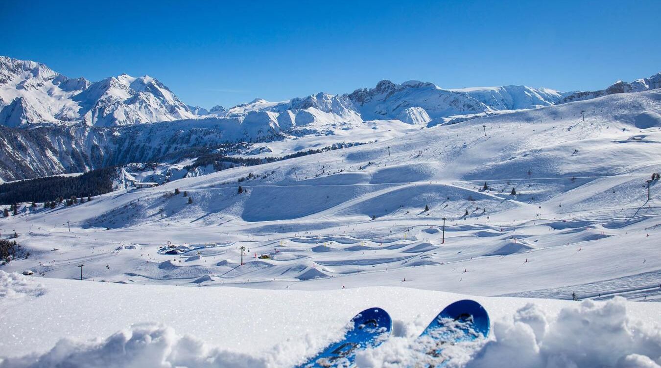 A snowy mountain landscape with ski slopes and a clear blue sky.