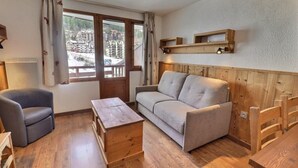 Una stanza accogliente con un divano, un tavolino in legno, una sedia e una panca di legno.