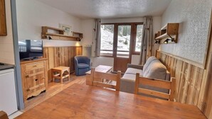 Una stanza accogliente con un tavolo in legno, un divano, una TV e una poltrona.
