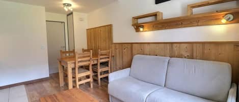 Ein Wohnzimmer mit Sofa, Holzesstisch, Stühlen und einem hölzernen Bettgestell.