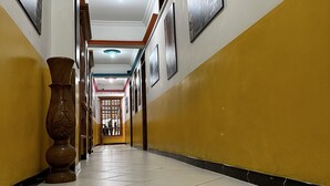 Un couloir avec un sol carrelé, des murs jaunes et des tableaux encadrés accrochés aux murs.