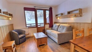 Et hyggeligt værelse med en sofa, en stol, et lille bord og en træbænk.