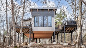 A modern treehouse with a central platform and two side platforms, surrounded by a forest. - Treehouse - Sunrise (Jonesburg)