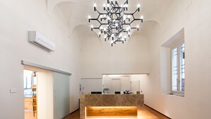 A spacious lobby with a central reception desk, a modern chandelier, and a large window on the right. - Bonacolsi Collection , Mantegna Hotels (Mantua)