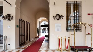 A hotel lobby with a red carpet, check-in desk, and a view of the courtyard. - Bonacolsi Collection , Mantegna Hotels (Mantua)