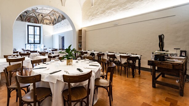 A spacious dining hall with round tables, wooden chairs, and a high arched ceiling. - Bonacolsi Collection , Mantegna Hotels (Mantua)
