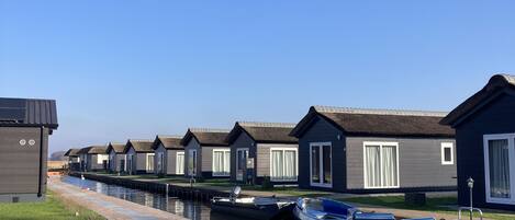 Une rangée de maisons flottantes sur l’eau, avec un canal en premier plan.