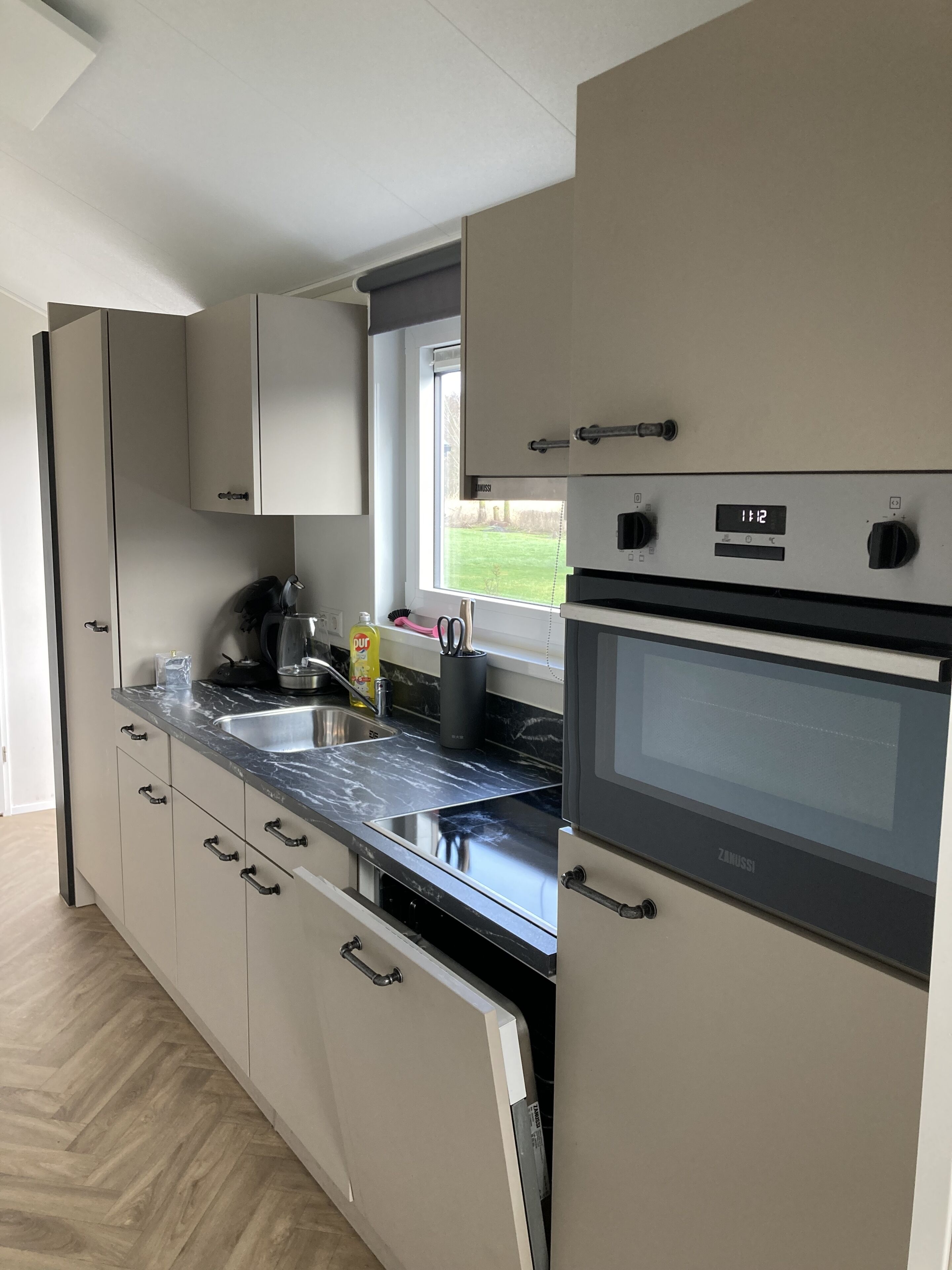 Una cocina moderna con horno empotrado, un fregadero y una ventana con vistas al exterior.
