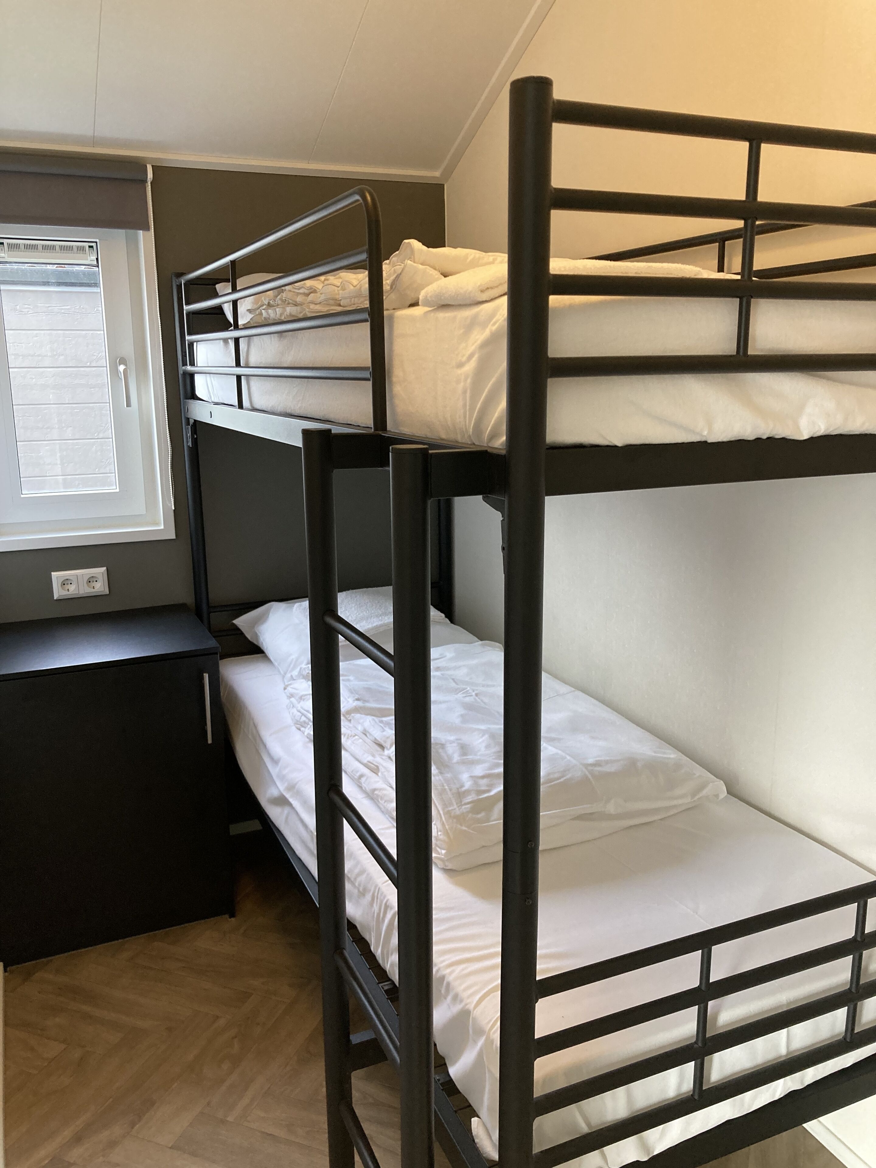 A bunk bed room with a desk and a window.