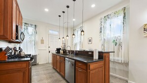Una cocina moderna con armarios de madera, una isla central, electrodomésticos de acero inoxidable e iluminación colgante.