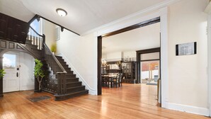 Un vestíbulo amplio con una escalera de madera, un comedor y vista a la cocina.
