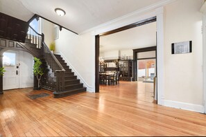 Un hall d’entrée spacieux avec un escalier en bois, un coin repas et une vue sur la cuisine.