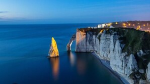A coastal cliff with a prominent rock formation and a town in the background. - Maison 2 à 6 Pers - En Plein Coeur de la Capitale du lin ! (Yvecrique)